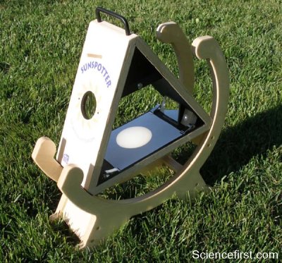 The photo shows the Sunspotter with a front lens held in a wood frame that can be orientated to the Sun. An image of the sun is projected onto a screen that can be viewed by a group on either side of the device.